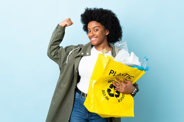 Young woman holding a recycle bag isolated on colorful doing strong gesture