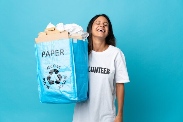 Young woman holding a recycling bag full of paper laughing