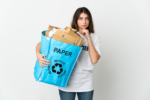 Young woman holding a recycling bag full of paper to recycle isolated on white thinking