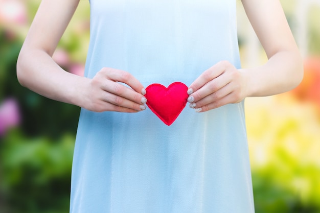 Young woman holding a red heart in her hands 