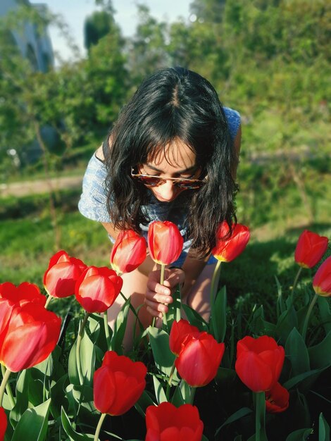 Young woman holding red tulip in garden