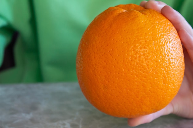 Young woman holding a ripe orange in her hand with copy space. Healthy lifestyle concept.