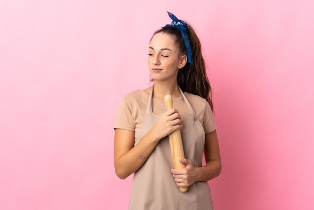 Young woman holding a rolling pin having doubts while looking side