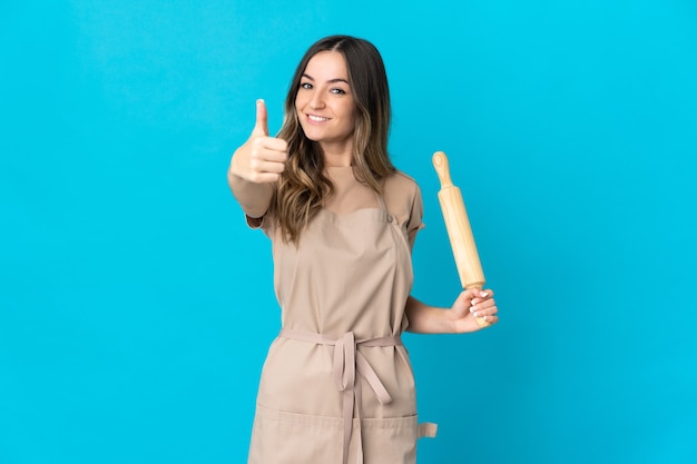 Young Woman holding a rolling pin isolated with thumbs up