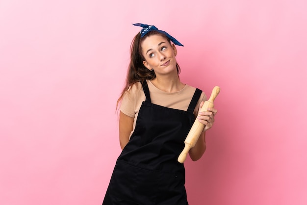 Young woman holding a rolling pin and looking up