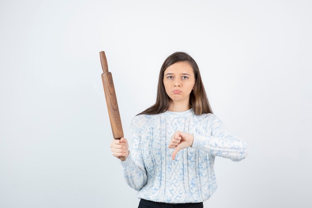 Photo young woman holding a rolling pin on white background