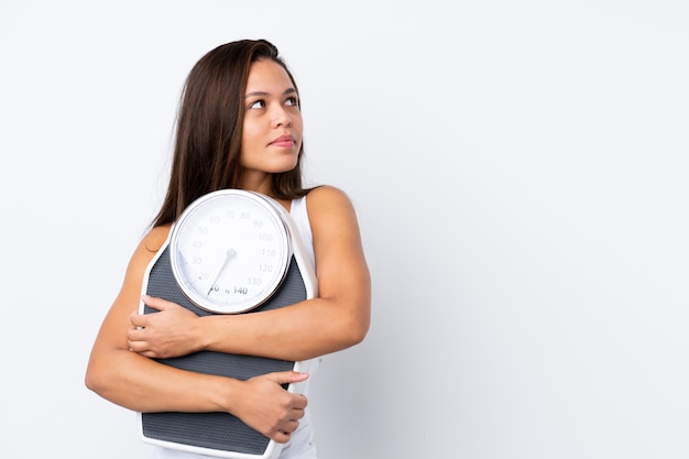 Young woman holding a scale over isolated wall