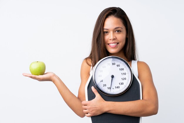 Young woman holding a scale over isolated wall