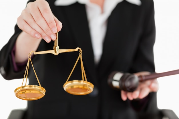 Young woman holding scales of justice and a gavel with the camera focus on the scales