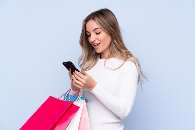 Young woman holding shopping bags over isolated wall