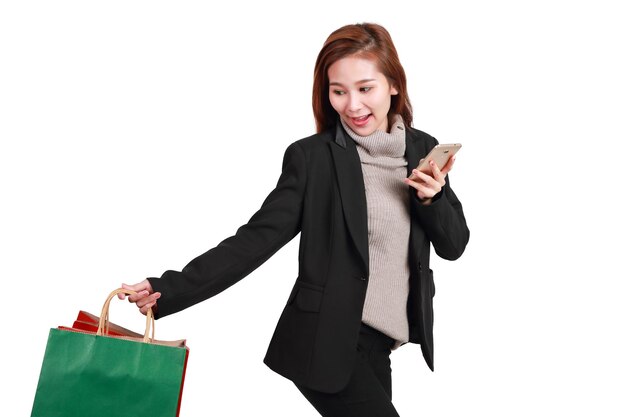 Young woman holding shopping bags and mobile phone against white background