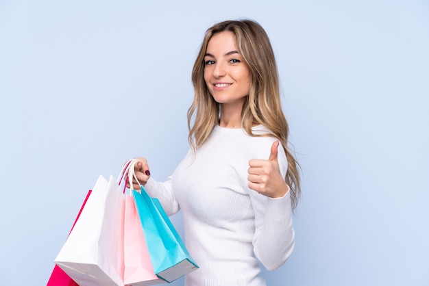 Young woman holding shopping bags and with thumb up