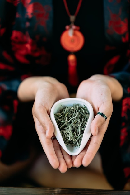 Young woman holding a small bowl of green herbal tea