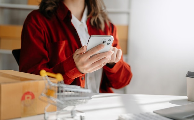 Foto giovane donna che tiene uno smartphone che mostra il successo del pagamento e la carta di credito con la cassetta dei pacchi gialla come concetto di shopping online