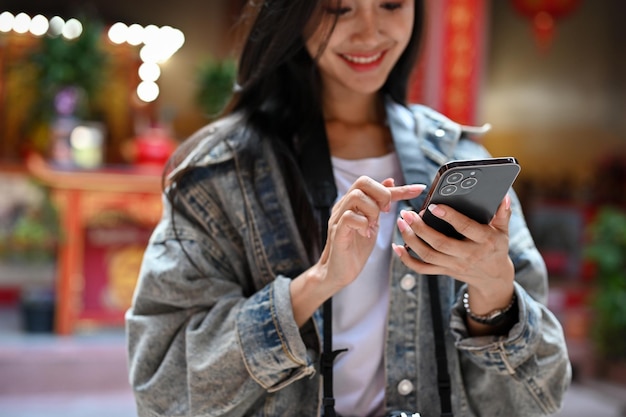 아시아 전통 사원을 여행하는 동안 스마트폰을 들고 있는 젊은 여성