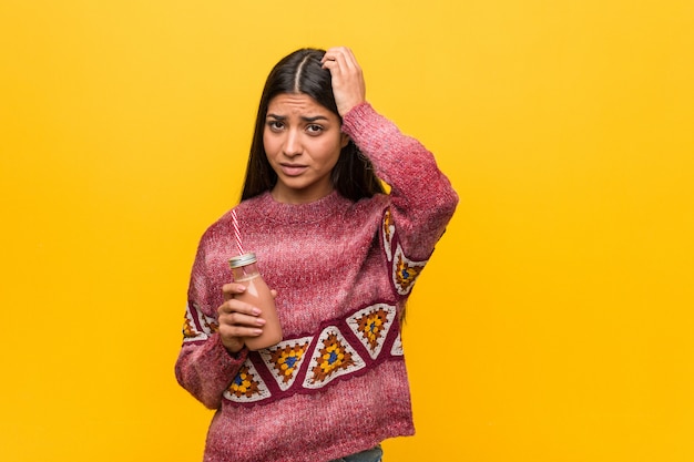 Young woman holding a smoothie being shocked, she has remembered important meeting