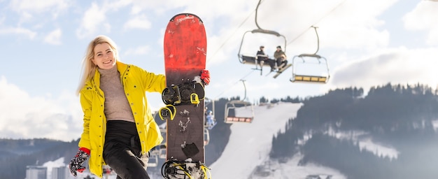 Young woman holding snowboard at winter resort