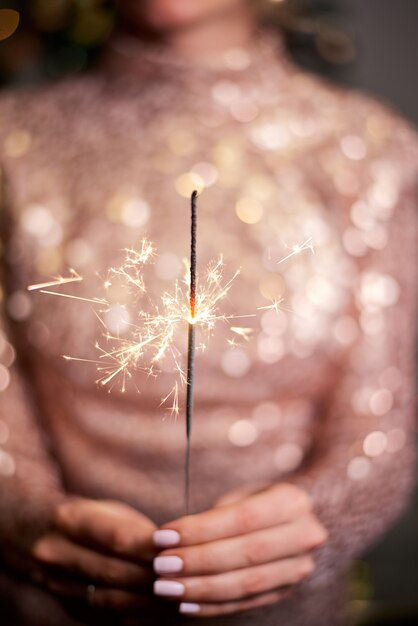 Young woman holding sparkler in hands