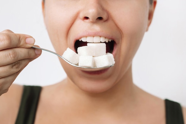 A young woman holding a spoon with cubes of refined sugar near her mouth