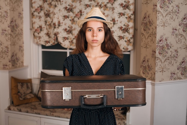 Young woman holding suitcase in her hands.