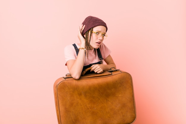 Молодая женщина, держащая чемодан пытается слушать сплетни