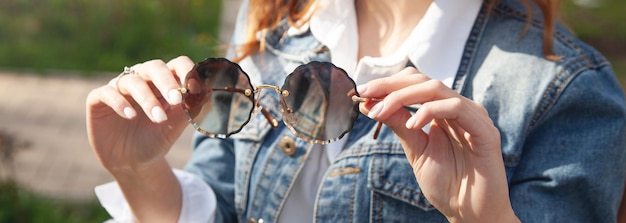 야외에서 선글라스를 들고 있는 젊은 여성