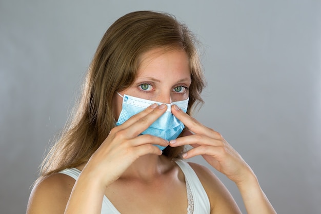 Young woman holding a surgical mask on the nose.