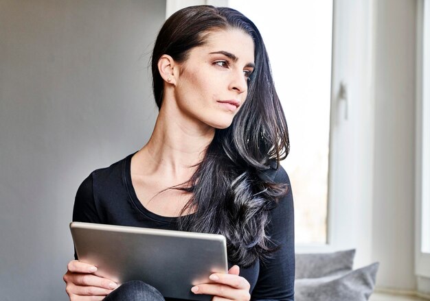 Young woman holding tablet looking sideways