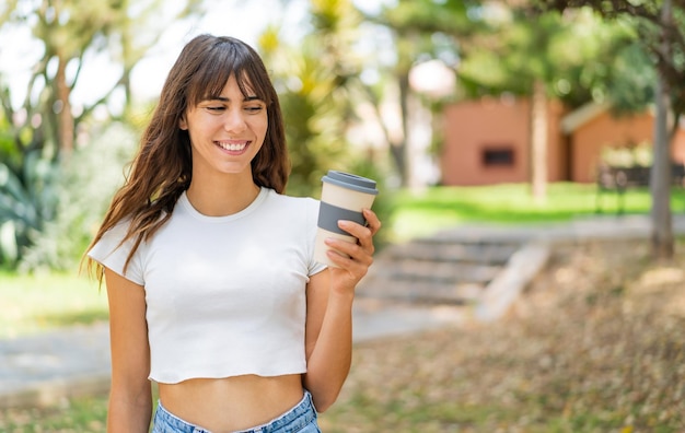 Foto giovane donna che tiene un caffè da asporto all'aperto con felice espressione