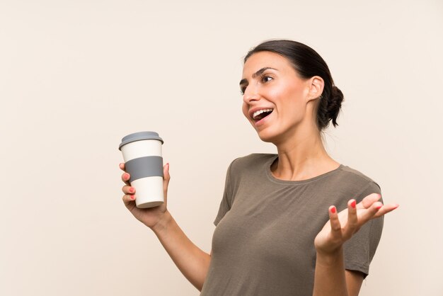 Giovane donna che tiene un caffè da asporto con espressione facciale a sorpresa