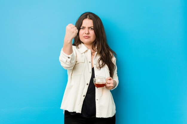 Young woman holding a tea cup showing fist