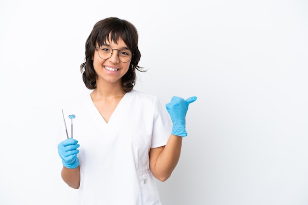 Young woman holding tools isolated on white background pointing to the side to present a product