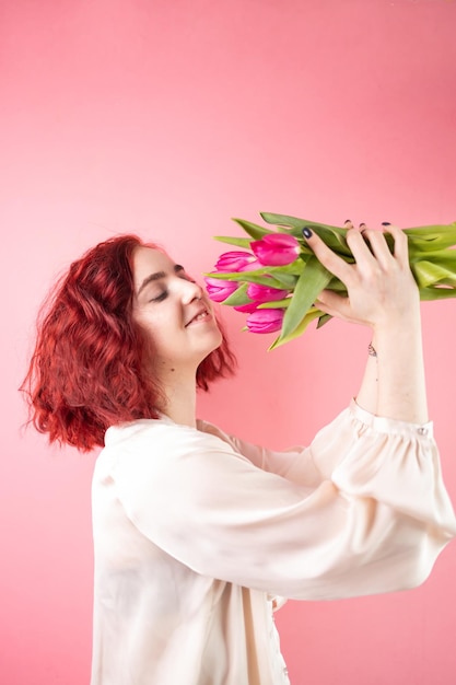 Фото Молодая женщина с тюльпанами на розовом