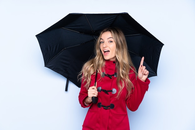 Young woman holding an umbrella over isolated wall