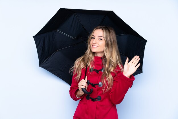 Young woman holding an umbrella over isolated wall