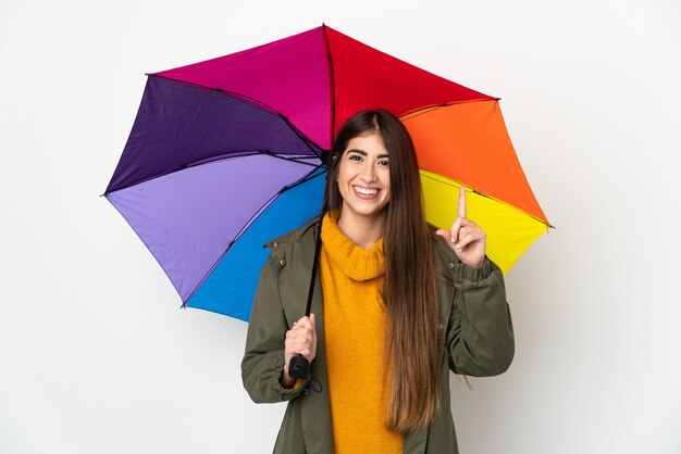 Young woman holding an umbrella isolated on white background pointing up a great idea