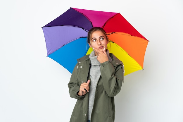 Молодая женщина, держащая зонтик, изолированная на белом пространстве, сомневается