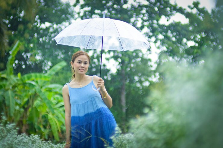 Photo young woman holding umbrella while standing in rain