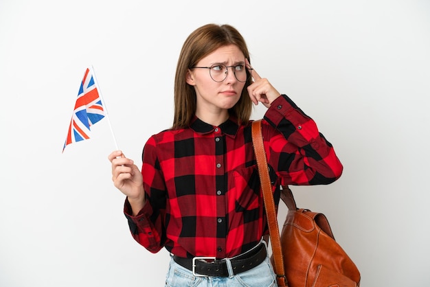 疑問と思考を持っている青い背景に分離されたイギリスの旗を保持している若い女性