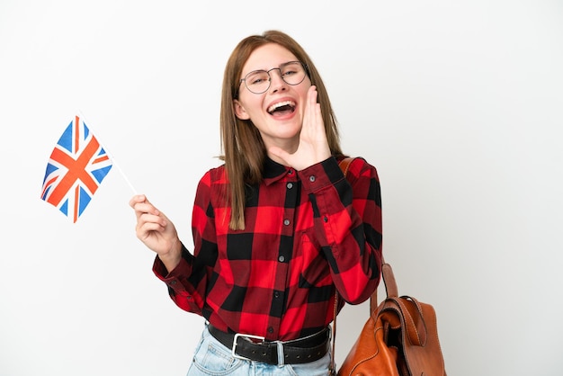 Young woman holding an United Kingdom flag isolated on blue background shouting with mouth wide open