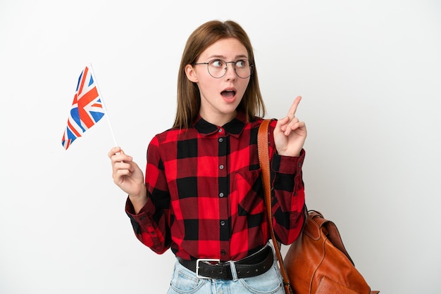 파란색 배경에 고립 된 영국 국기를 들고 손가락을 가리키는 아이디어를 생각 하는 젊은 여자
