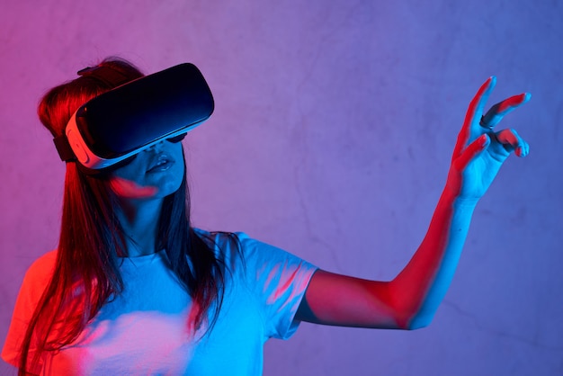 Young woman holding virtual reality helmet while wearing a white t-shirt