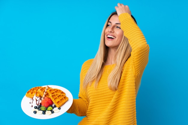 Photo young woman holding waffles over isolated wall has realized something and intending the solution