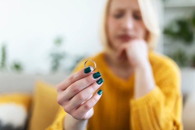 Young woman holding wedding engagement ring in hands, engaged girl doubts about marriage proposal, abandoned wife depressed after getting divorced, help to overcome breaking up, starting new life