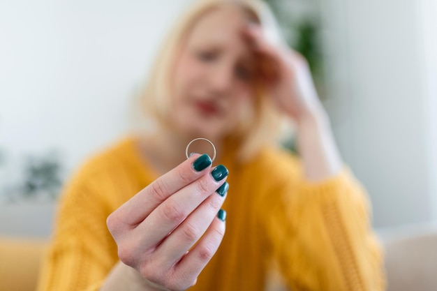 Young woman holding wedding engagement ring in hands engaged girl doubts about marriage proposal abandoned wife depressed after getting divorced help to overcome breaking up starting new life