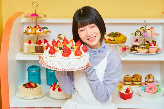 Foto una giovane donna che tiene in mano un'intera torta