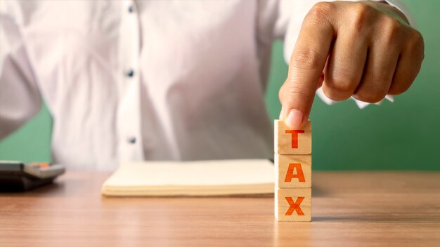 Young woman holding a wooden cube with the word Tax, financial concept. Financial Management and Tax Planning