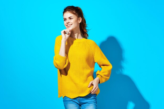 Young woman holding yellow while standing against blue background