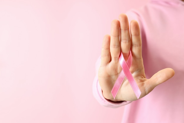 Young woman holds breast cancer awareness ribbon, close up