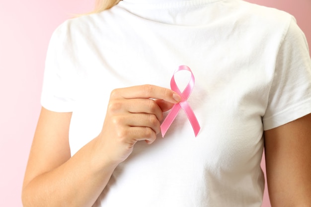 Young woman holds breast cancer awareness ribbon, close up